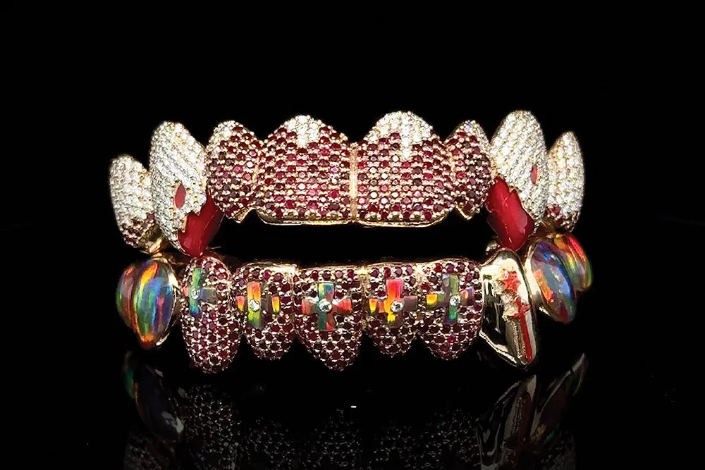 A close crop of red and clear jeweled dental grills with prominent side fangs.