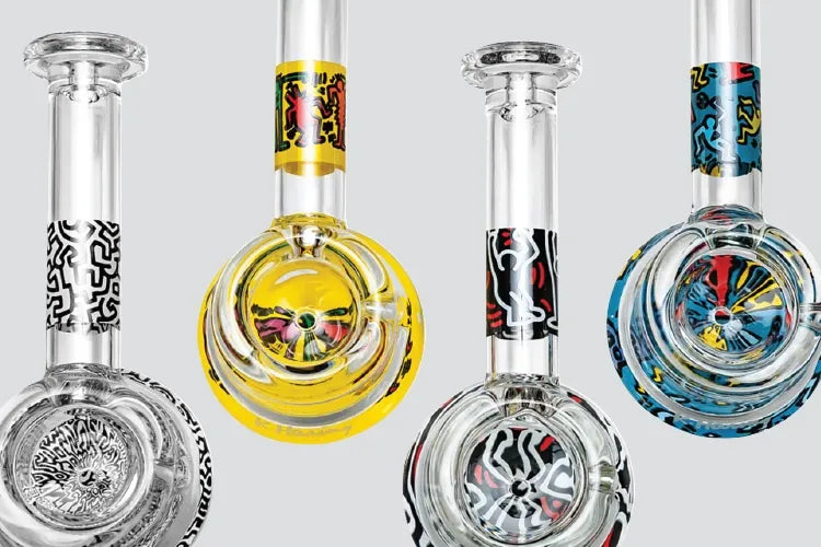 A close crop of four colorful Keith Haring glass spoon pipes.