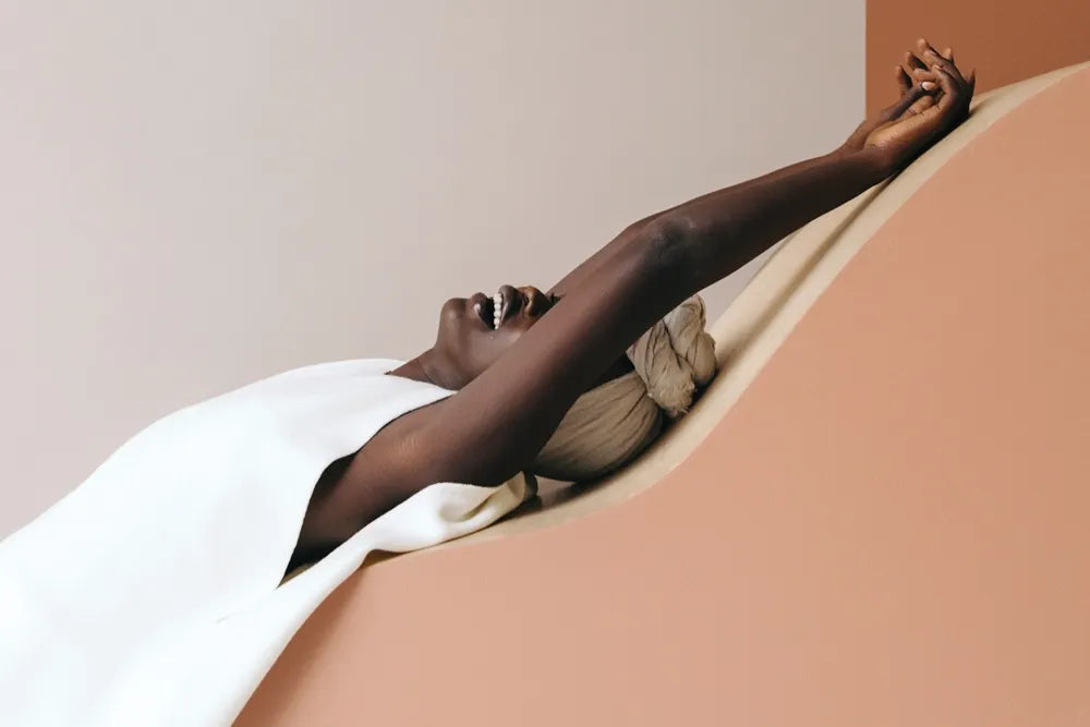 A person reclines in a curved seat with one arm stretched above their head.