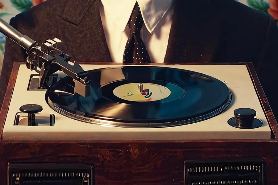 A record spins on a turntable in front of a suited listener.