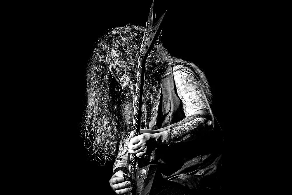 Black-and-white photograph of Dimebag Darrell bent over his electric guitar.