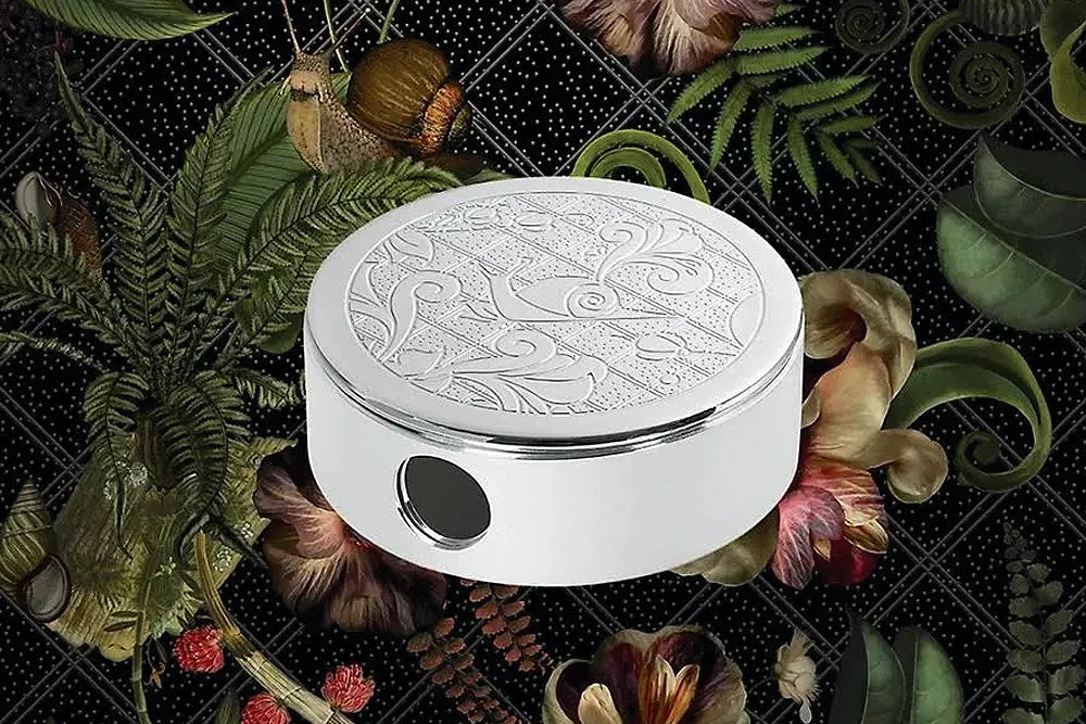 A round engraved Christofle ashtray surrounded by patterned foliage.
