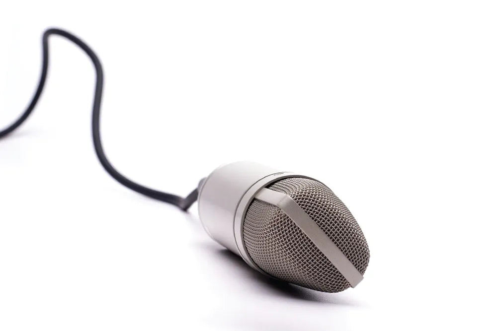 A silver handheld microphone with a black cable on white.