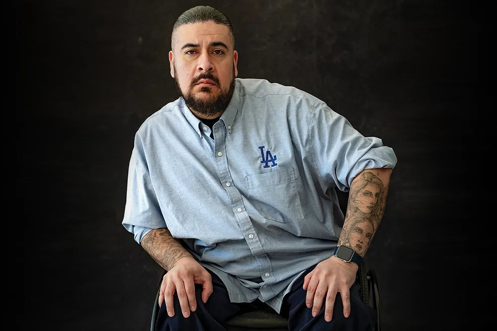 David Rios sits against a dark backdrop wearing a light blue Dodgers shirt.