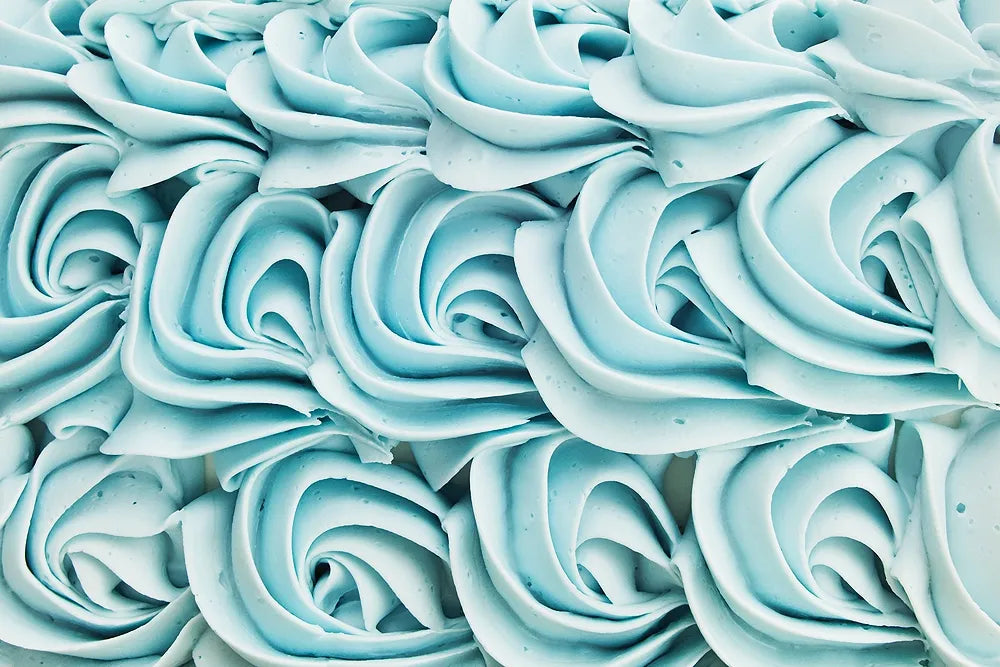Rows of pale blue buttercream rosettes piped across a cake.