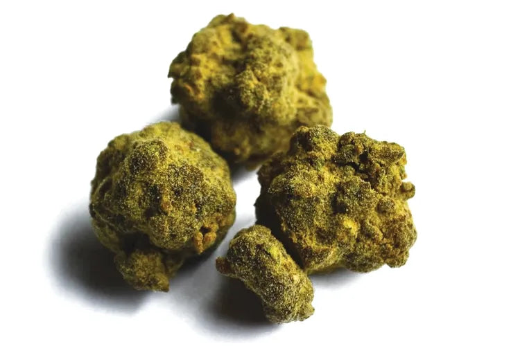 Three cannabis moon rocks coated in golden-green kief.