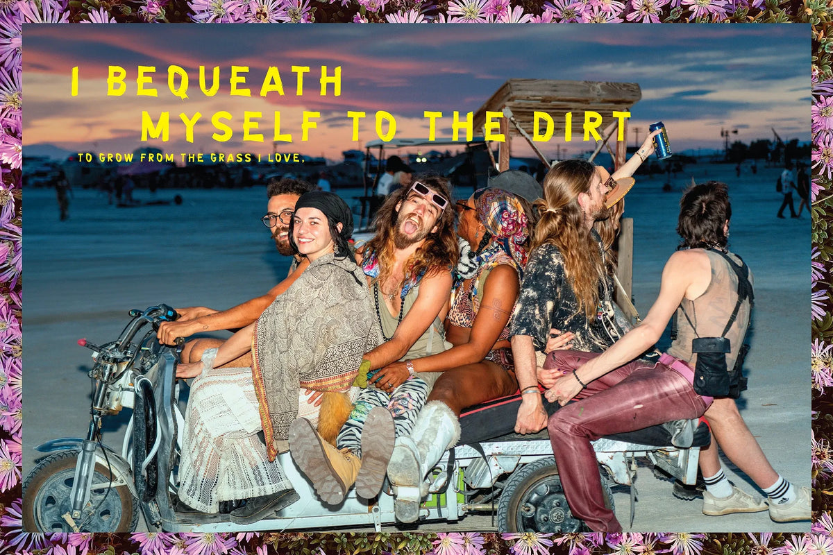 Festivalgoers ride together at Bombay Beach beneath the words “I bequeath myself to the dirt.”