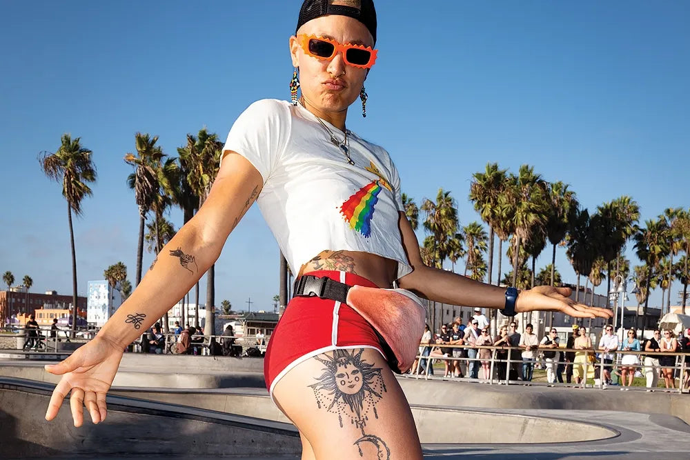 A roller skater in orange sunglasses poses at a sunny Venice Beach skatepark.
