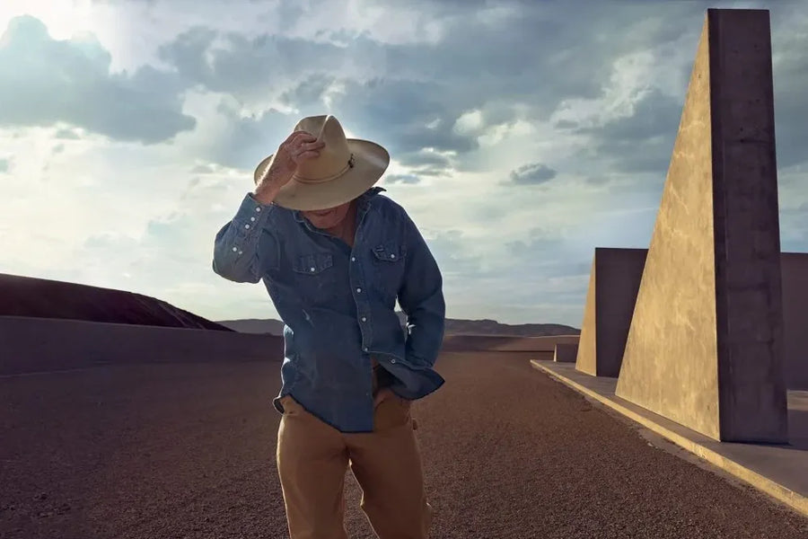 Story artwork: A closer view of a person in a cowboy hat among the earthworks at City.