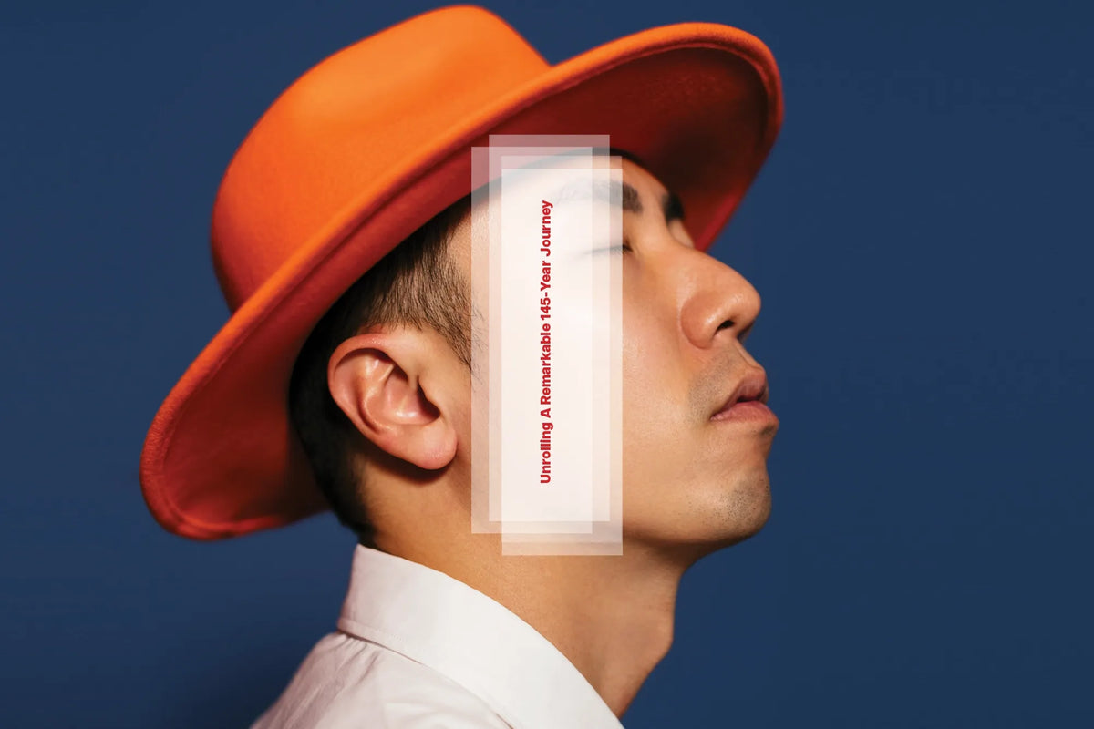 A person in an orange hat balances a rolling-paper booklet against their face.