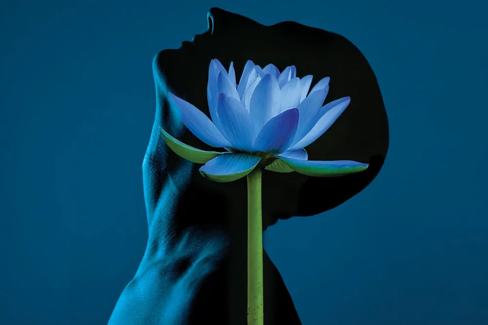 A blue lotus flower against the silhouette of a person's head and neck.