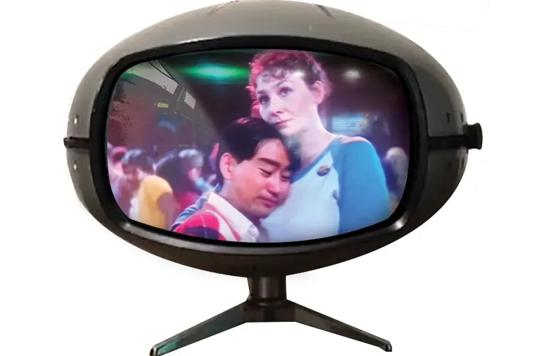A rounded vintage television displays a scene with two people.