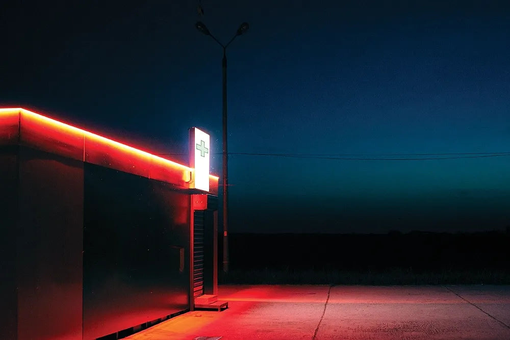 A small roadside shop outlined in red neon at night.