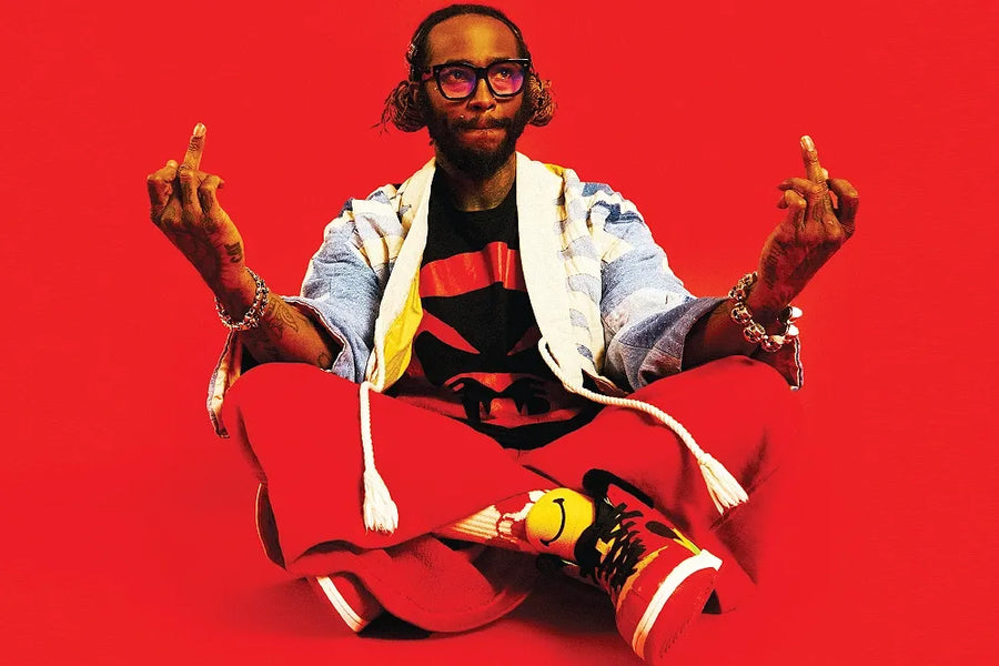 Story artwork: A seated model in glasses and colorful clothing gestures against a red backdrop.