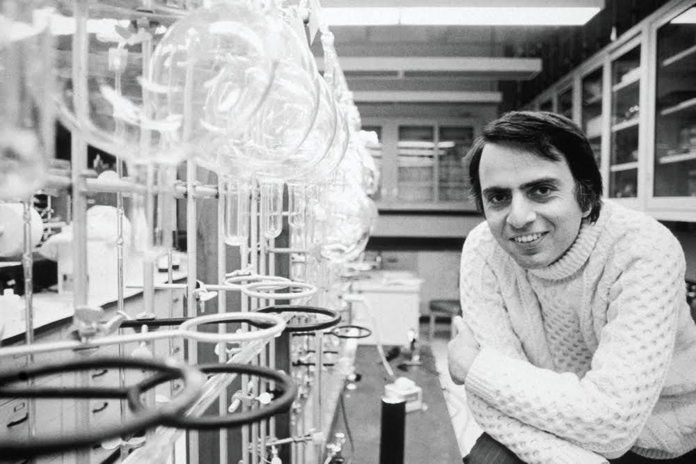 An archival black-and-white portrait of a scientist beside laboratory glassware.